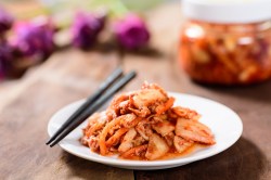 Kimchi selber machen: Eine Portion Kimchi in einer weißen Schale. Daneben liegen Essstäbchen.