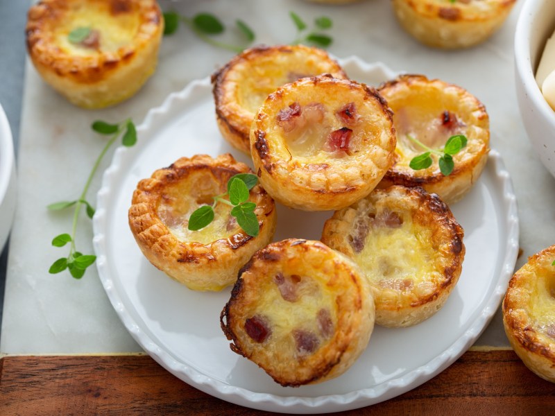 Mini-Quiche mit Schinken auf einem Teller.