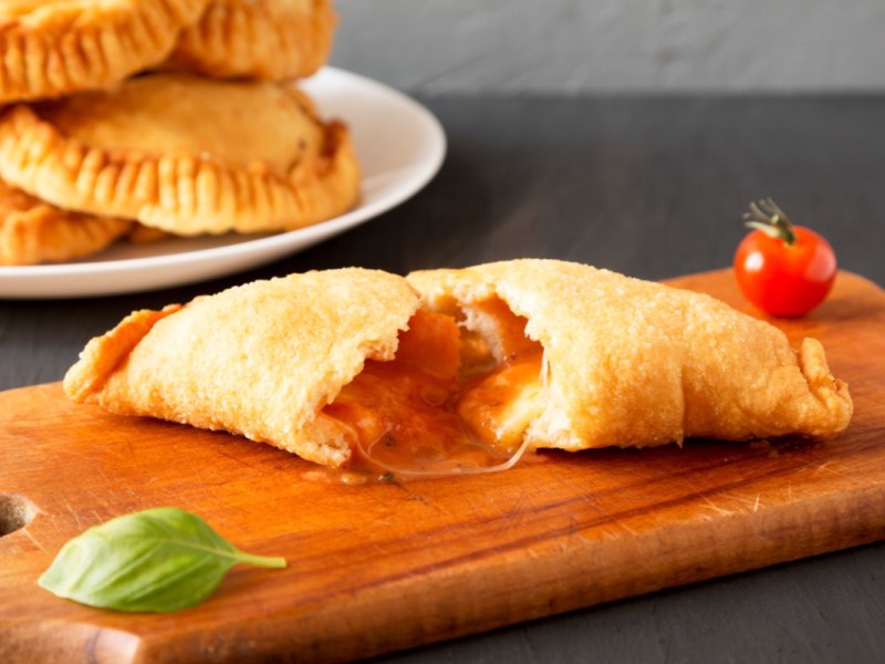 Ein Panzerotti mit Tomate-Mozzarella-Füllung, der in der Mitte durchgeschnitten wurde.