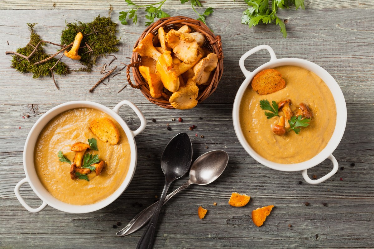 Zwei Schüsseln mit Pfifferlingcremesuppe und einer Schale Pfifferlingen.