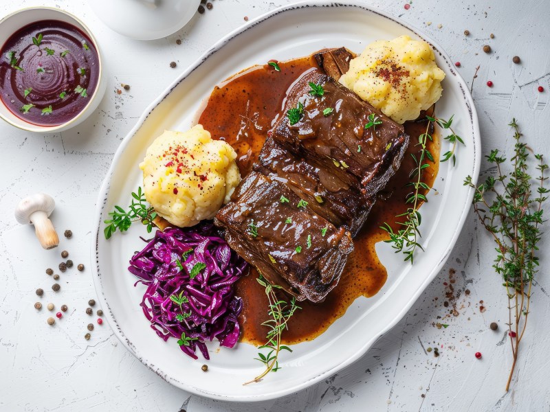 Teller mit Rheinischem Sauerbraten mit Kartoffelstampf und Rotkohl