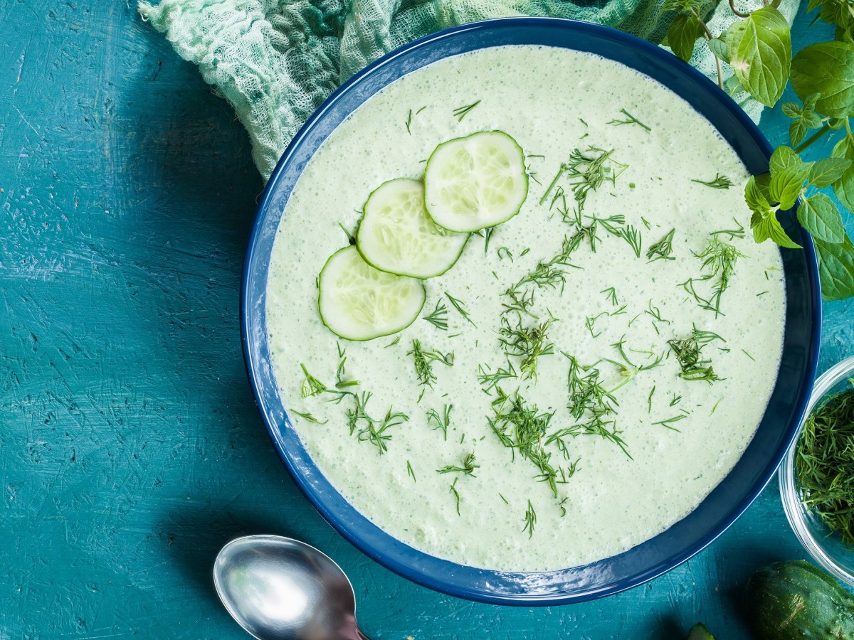 Schüssel mit kalter Spreewälder Gurkensuppe auf blauem Untergrund