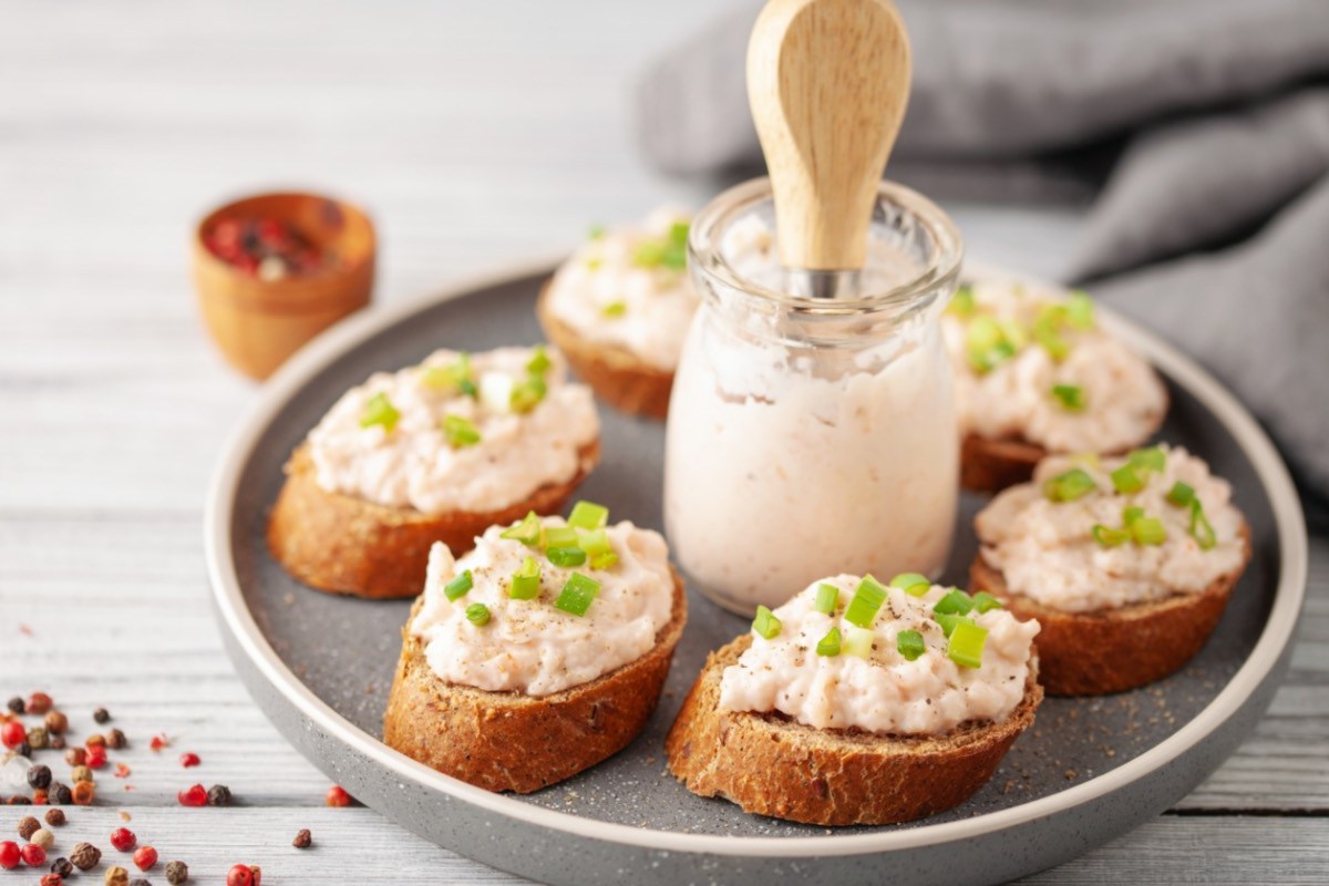 Thunfisch-Aufstrich auf mehreren Scheiben Baguette. In der Mitte steht ein Glas mit Aufstrich.