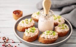 Thunfisch-Aufstrich auf mehreren Scheiben Baguette. In der Mitte steht ein Glas mit Aufstrich.