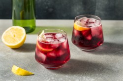 Zwei Gläser Tinto de Verano. Daneben liegt eine halbe Zitrone.