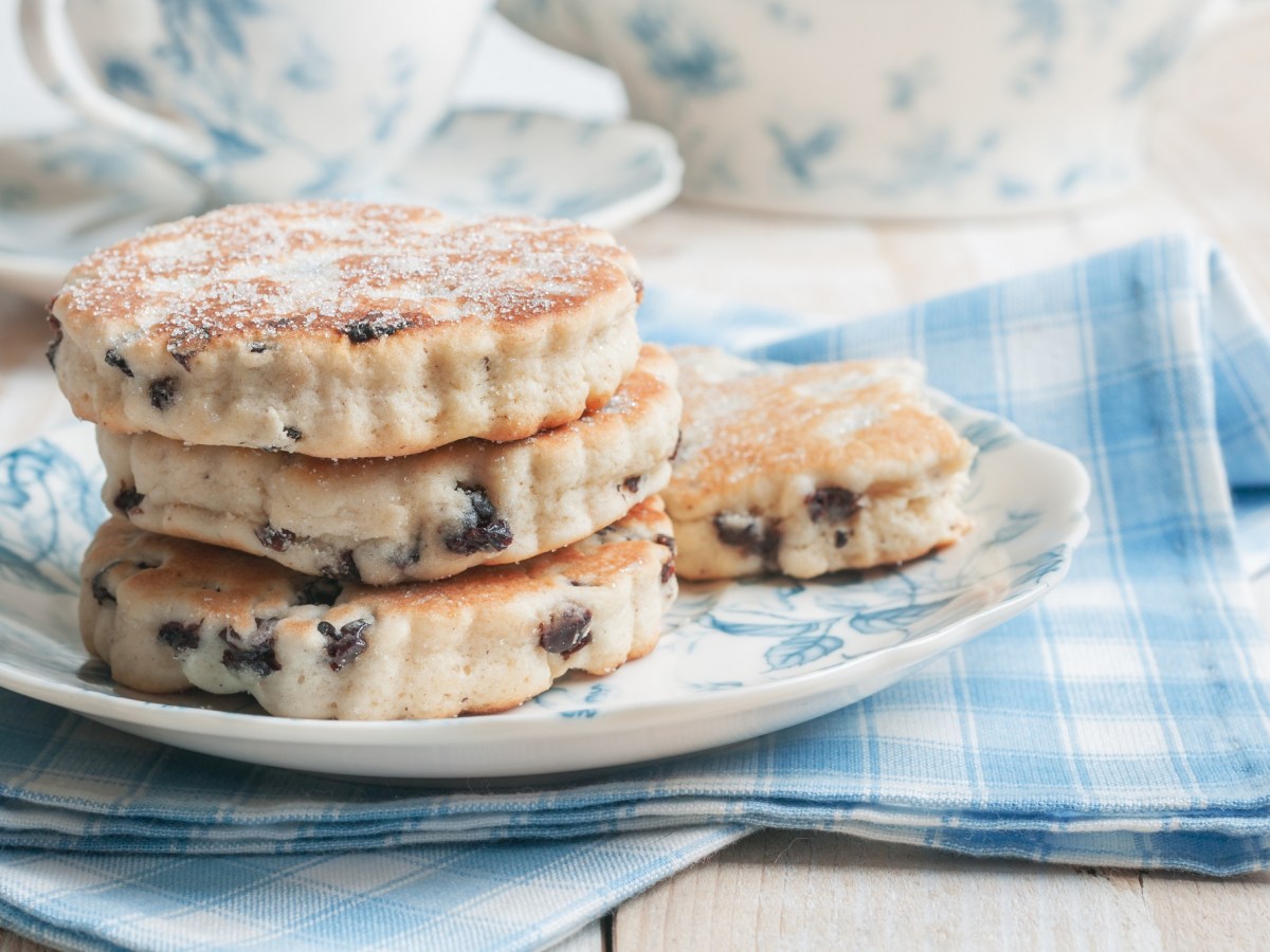 Welsh Cakes übereinandergestapelt auf einem Teller. Dieser steht auf einer blau-weiß-karierten Serviette.