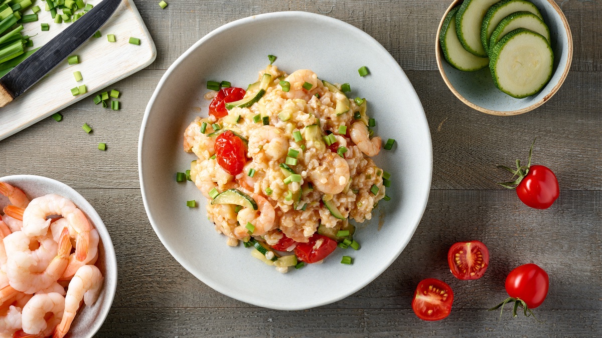 Zucchini-risotto-mit Garnelen auf einem weißen Teller.