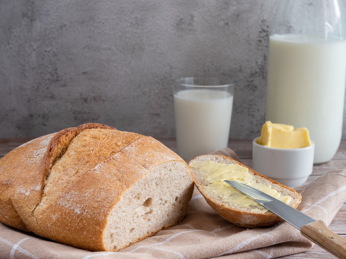 Angeschnittenes Buttermilchbrot mit Butter und Buttermilch auf einem Tisch