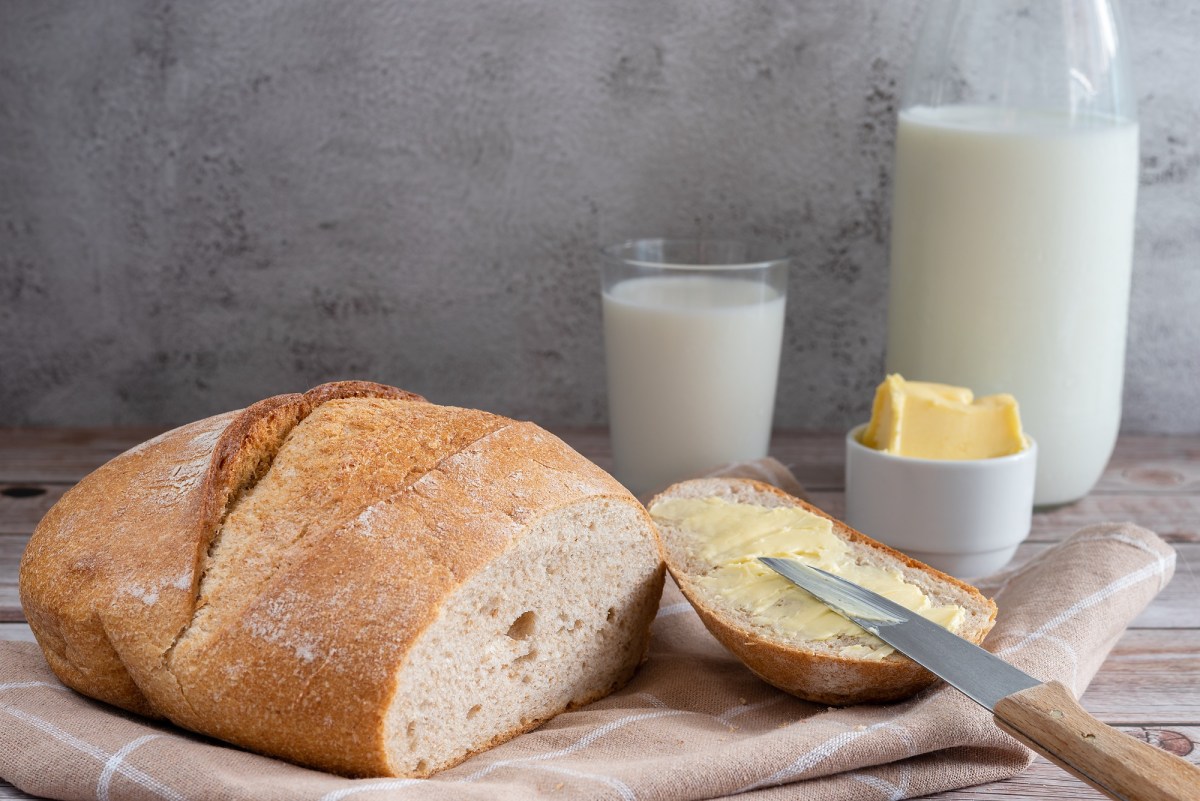 Angeschnittenes Buttermilchbrot mit Butter und Buttermilch auf einem Tisch