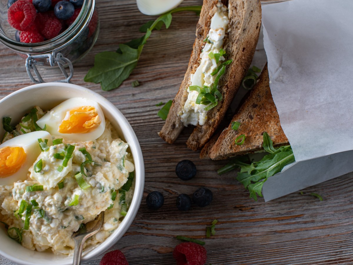 Eine Schale Eiersalat mit Hüttenkäse und belegte Brote