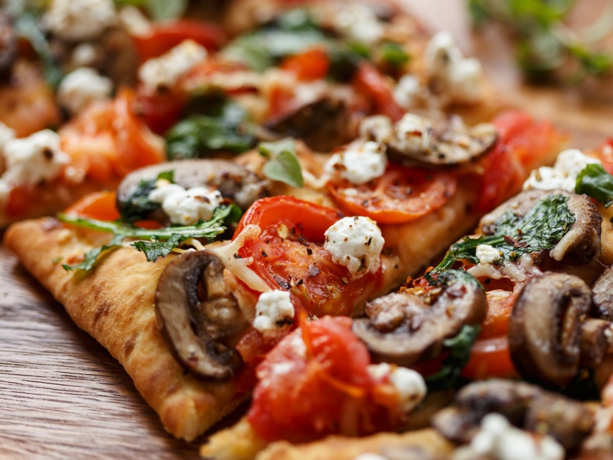 In Stücke geschnittene Fladenbrot-Pizza mit Pilzen, Feta und Tomaten.