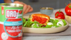 gebackener Tomaten-Taler auf einem Teller mit Mozzarella und Rucola, davor eine Dose mit Feinstem Tomatenfruchtfleisch Pulpo fine von ORO di Parma.