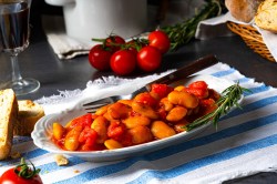 dicke Bohnen in Tomatensoße auf einem ovalen Teller.