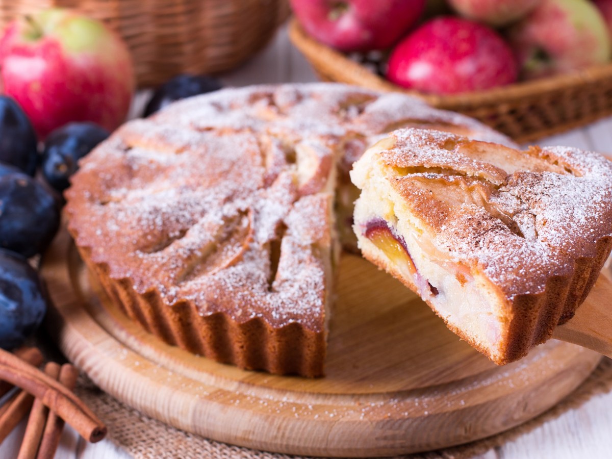 Ein Pflaumen-Apfel-Kuchen auf einem Holzbrett.