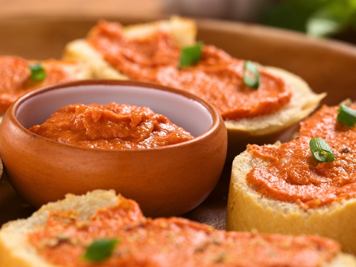 Eine Schale Tomatenbutter, drumherum Baguettescheiben mit der Butter bestrichen.