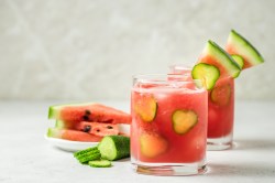 Zwei Gläser Wassermelonen-Mojito, geschnittene Melone daneben