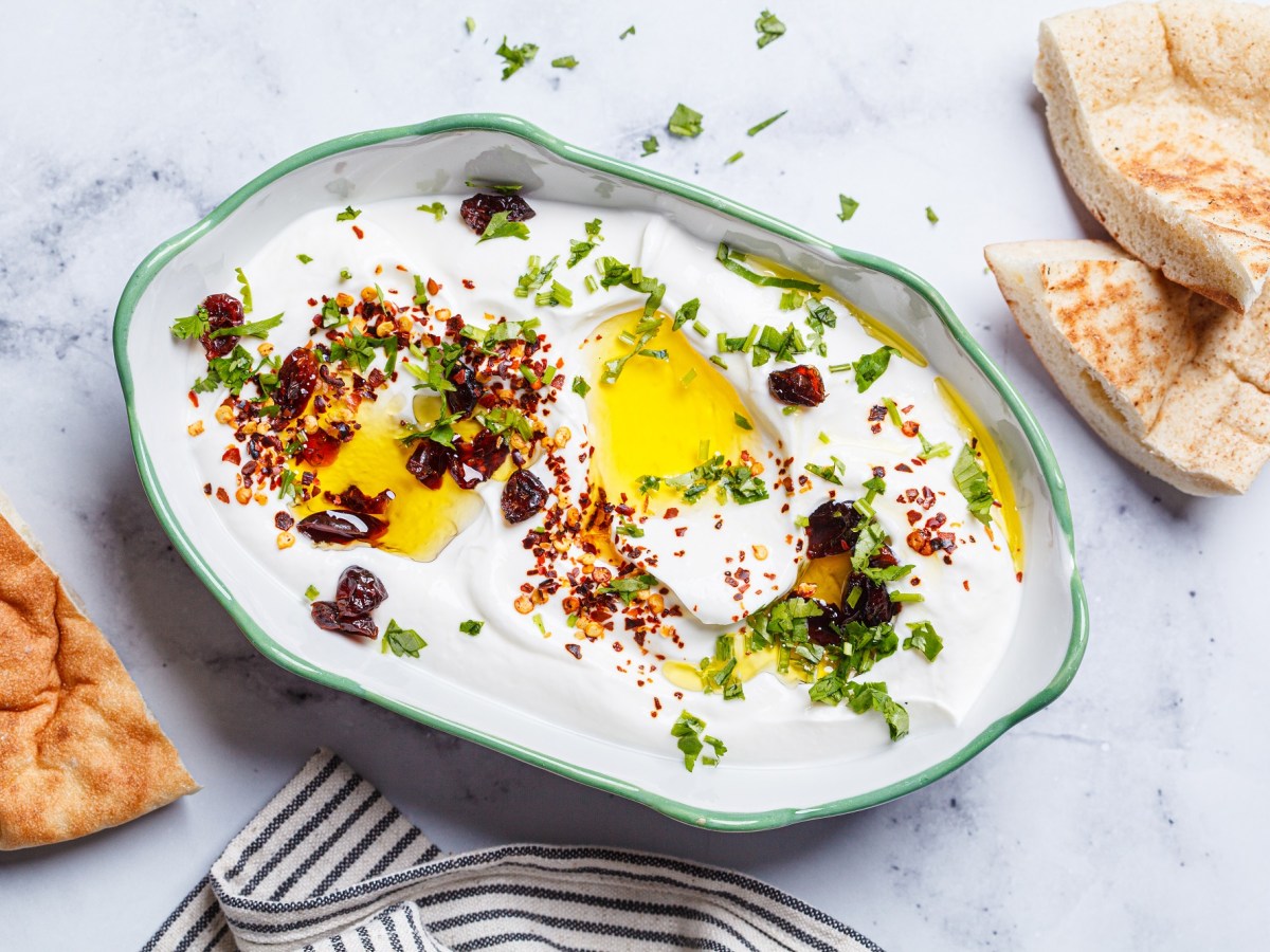 Whipped Feta-Dip, garniert mit Öl, Petersilie und Chili, in einer Schüssel mit grünem Rand.