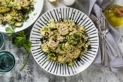 Zucchini-Reissalat auf einem blau-weiß gestreiften Teller.