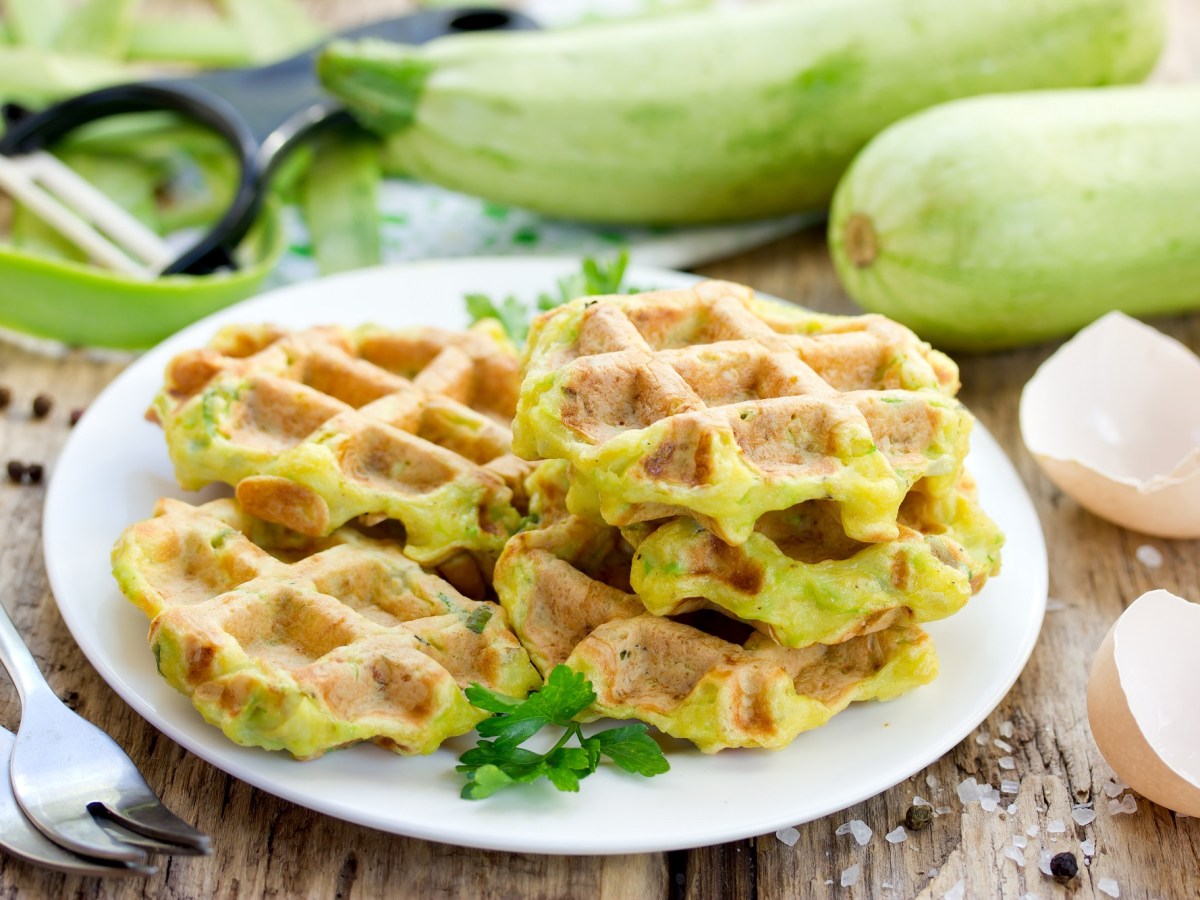 Zucchini-Waffeln mit Frischkäse auf einem Teller.