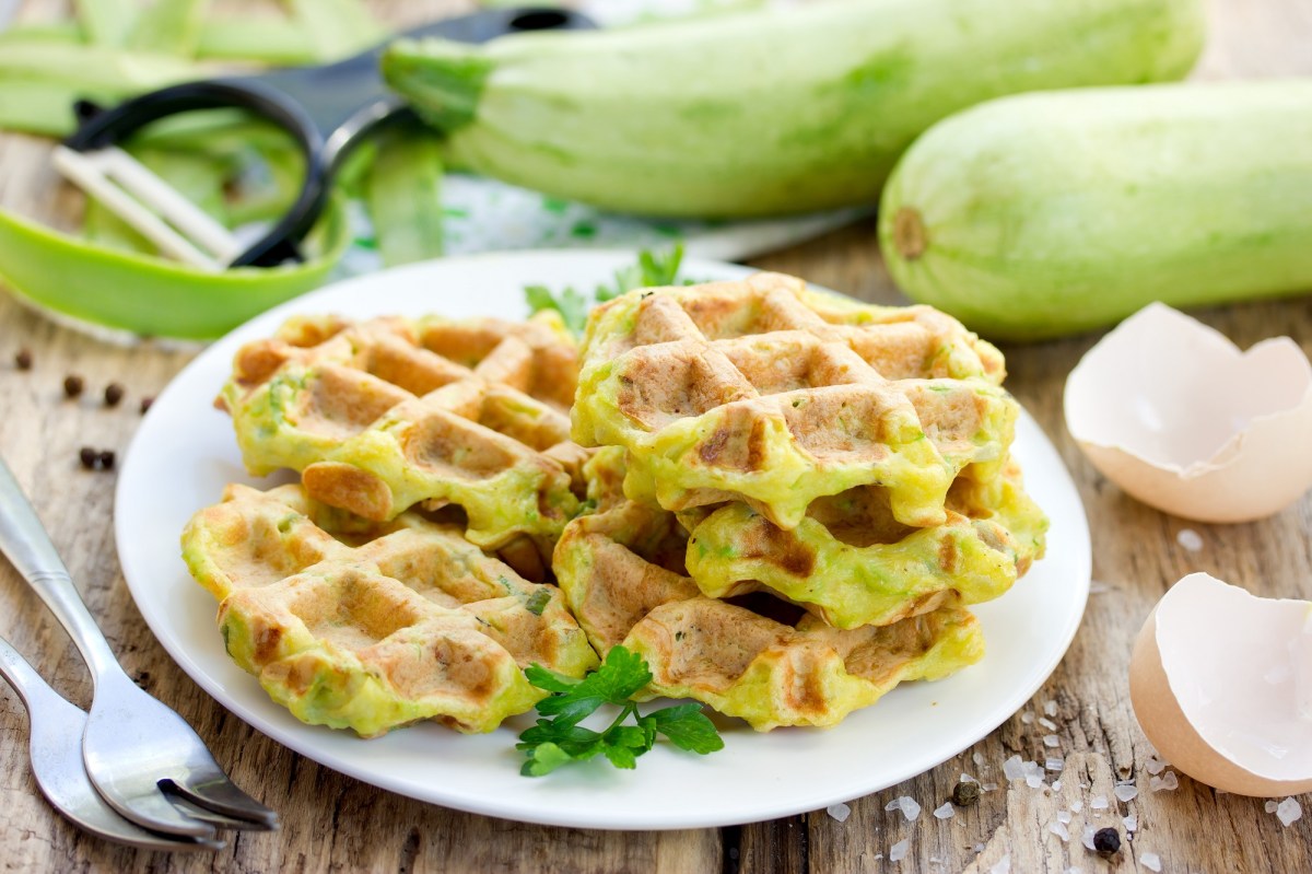 Zucchini-Waffeln mit Frischkäse auf einem Teller.