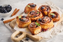 Blaubeer-Zimtschnecken auf einem Holzbrett.