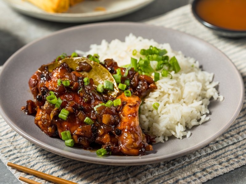 Chicken Adobo mit Reis auf einem grauen Teller.