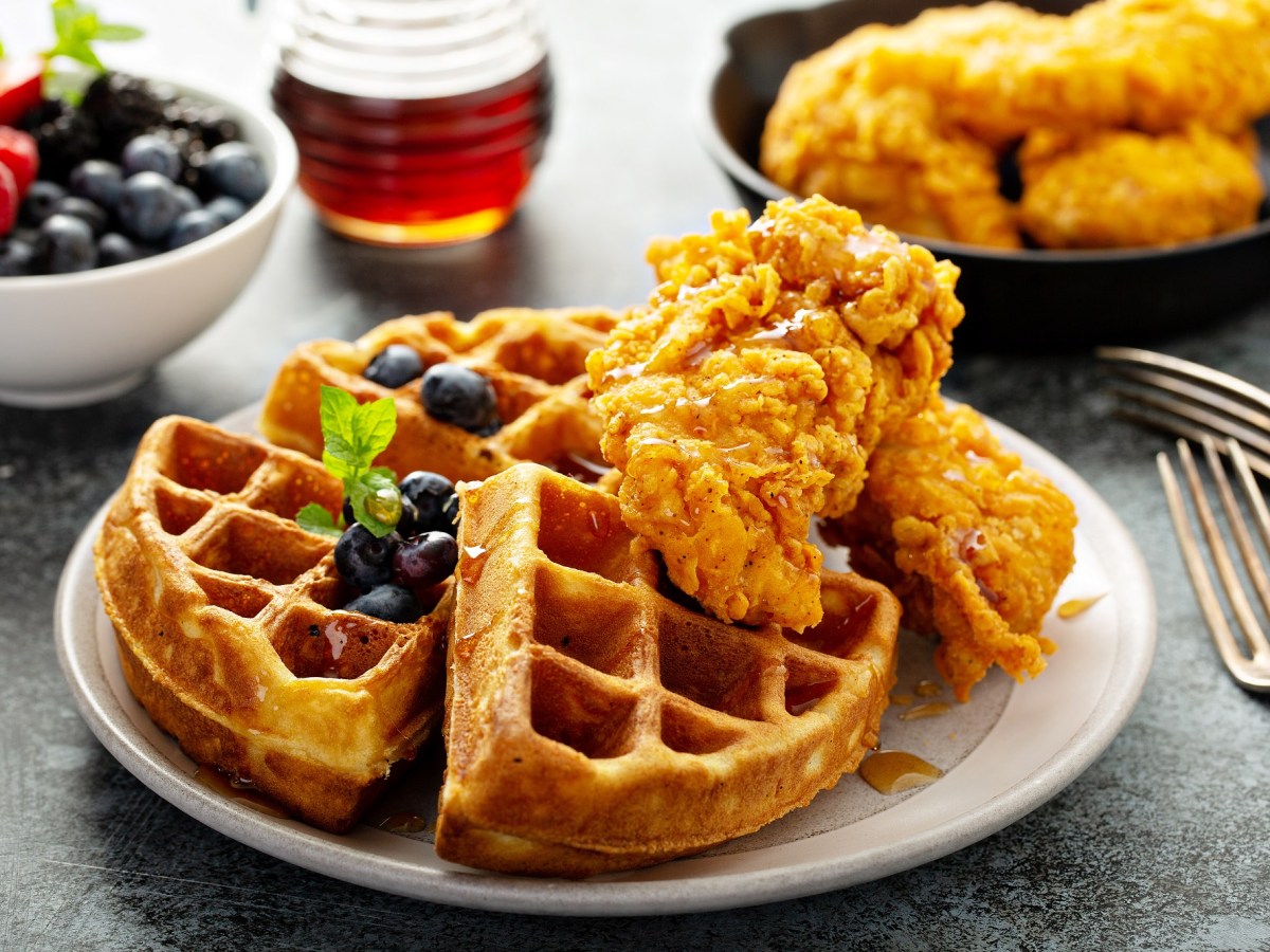 Chicken and Waffles auf einem Teller, serviert mit Blaubeeren.