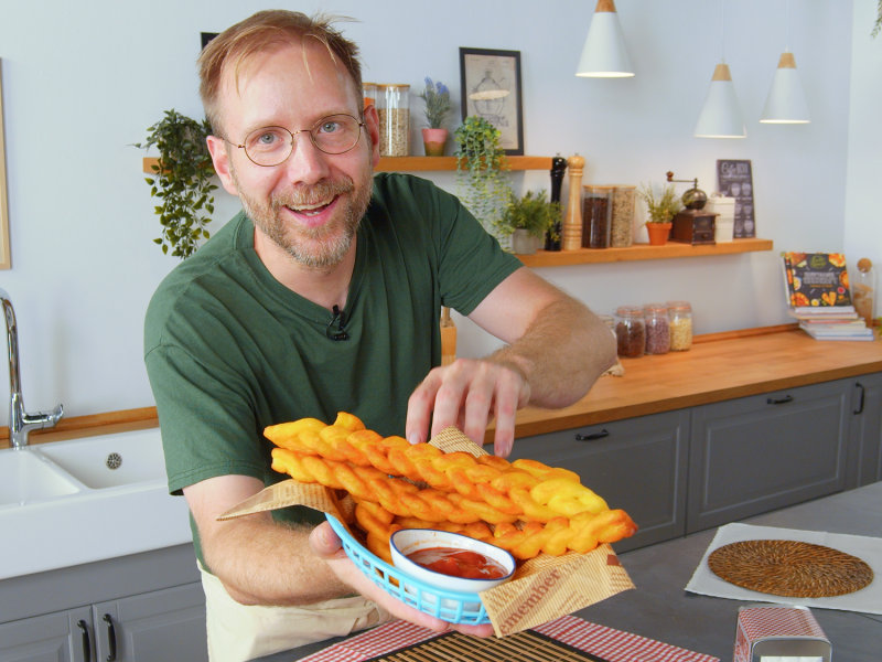 Koch präsentiert einen Teller mit geflochtenen Pommes