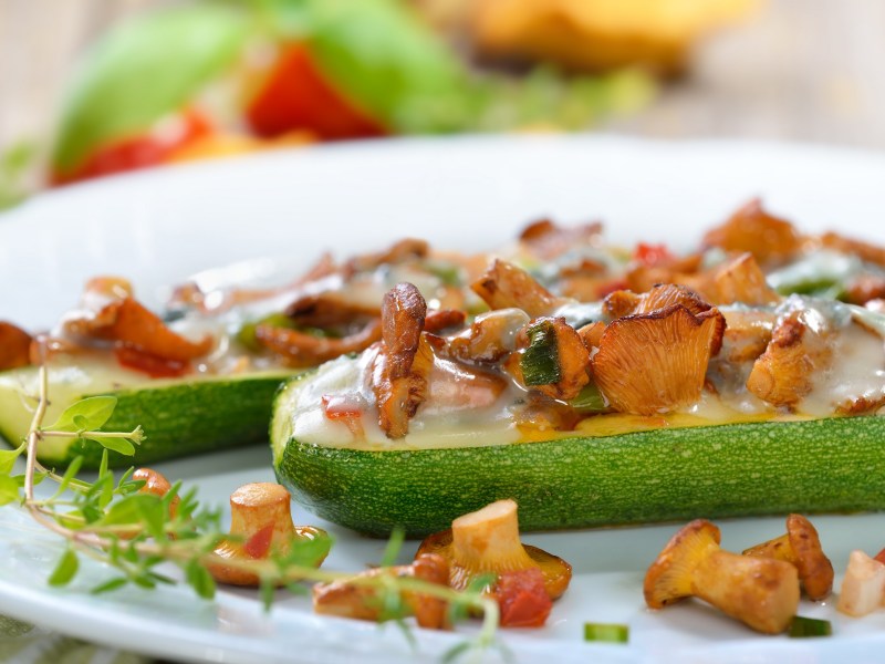 Gefüllte Zucchini mit Pfifferlingen auf einem Teller. Nahaufnahme.