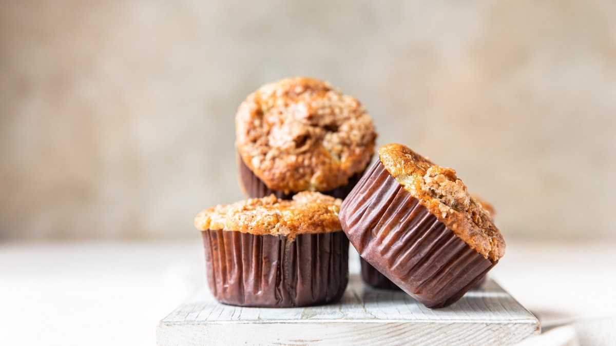 3 Kürbismuffins mit Streuseln in braunen Muffinförmchen.