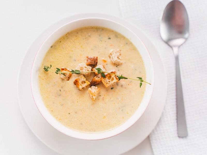 Schüssel mit Parmesan-Suppe und Löffel