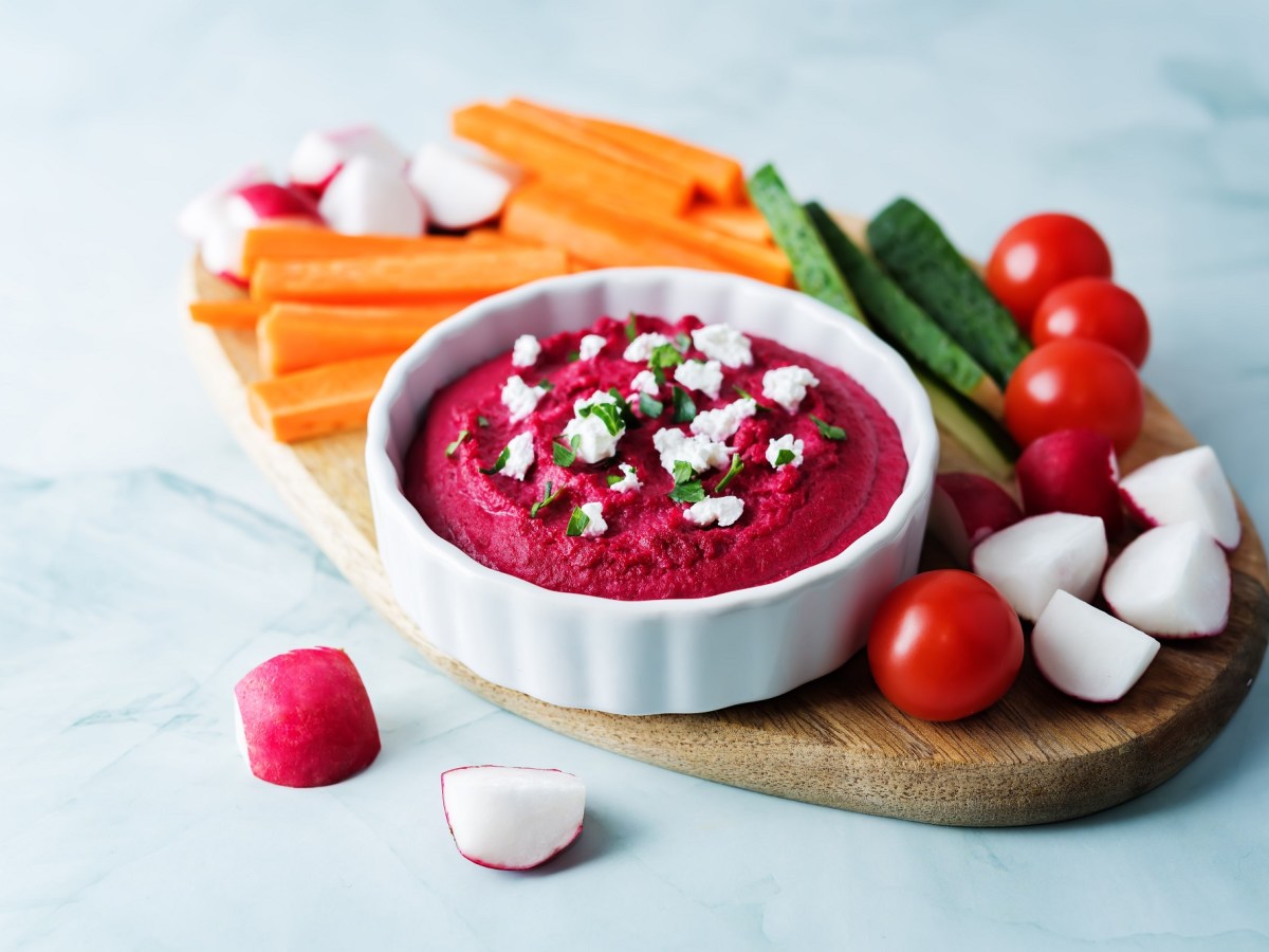 Schälchen mit Rote-Bete-Feta-Aufstrich und Gemüsesticks daneben.