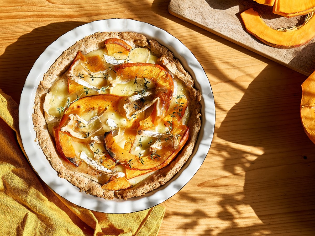 Eine Kürbis-Brie-Tarte auf einem Holztisch.