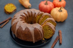 angeschnittener Kürbis-Gugelhupf mit Zimtglasur, Kürbisse daneben