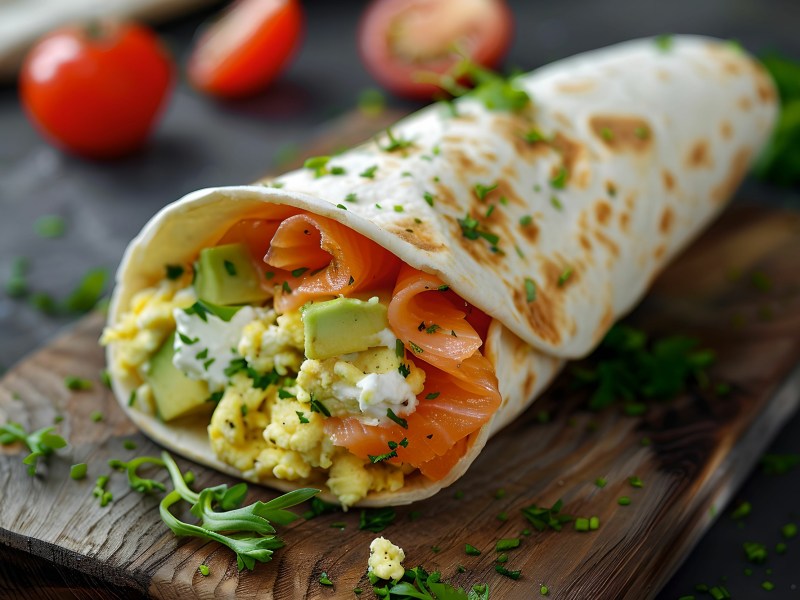 Rührei-Wrap mit Lachs und Avocado auf einem Brett