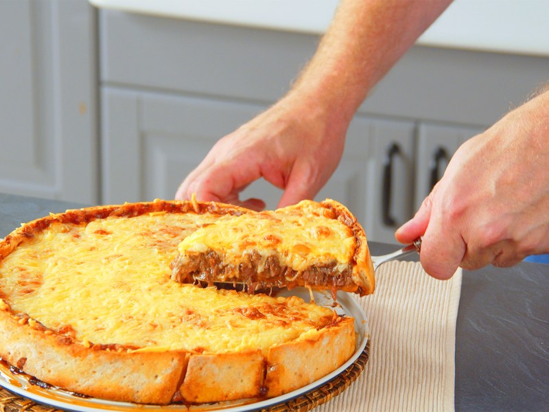 Tiefkühlpizza-Kuchen, aus dem ein Stück herausgenommen wird.