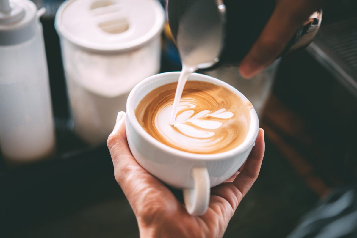 De'Longhi SiebtrÃ¤ger im Angebot bei Amazon: Ein Barista kippt Milch in eine Tasse Kaffee.