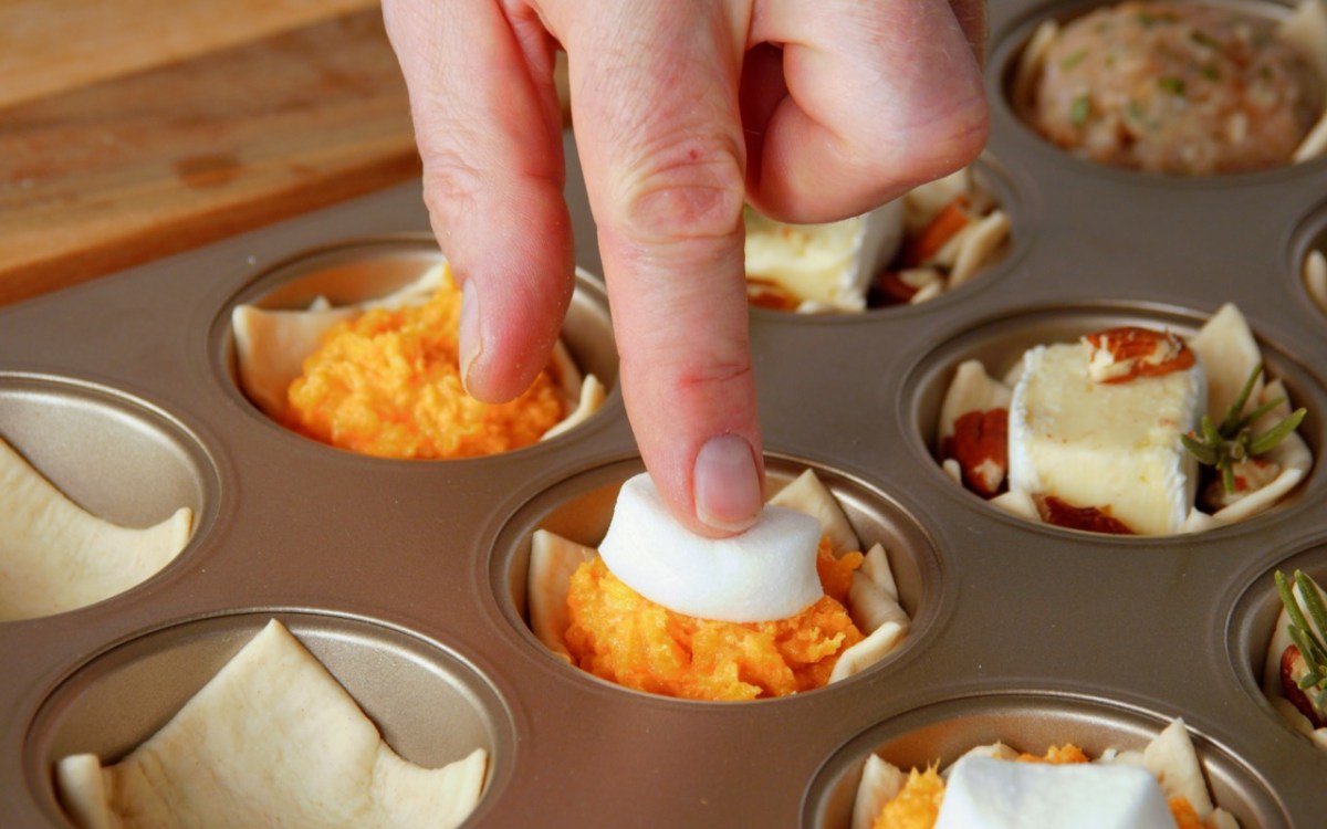 Fingerfood-Cups: Ein Marshmallow wird auf Kartoffelbrei aus Süßkartoffel in einem Muffinblech gedrückt.