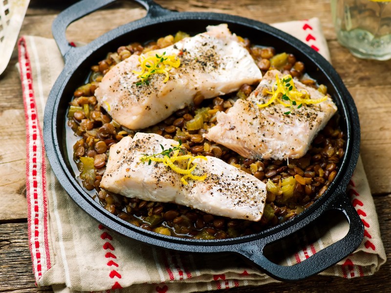 Ein paar Fischfilets mit Linsengemüse.