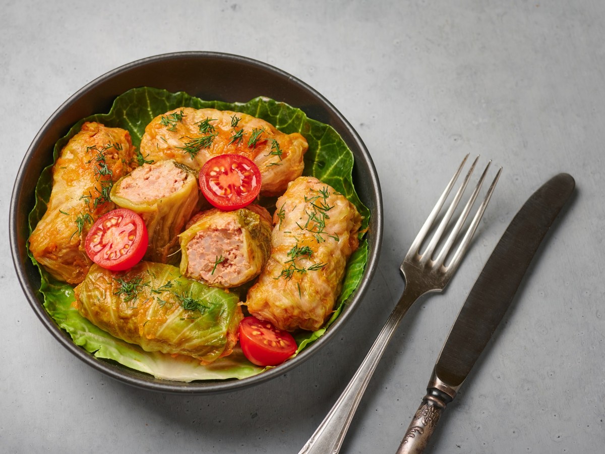 Polnische Kohlrouladen, in einer Schale angerichtet. Garniert sind sie mit halbierten Tomaten.