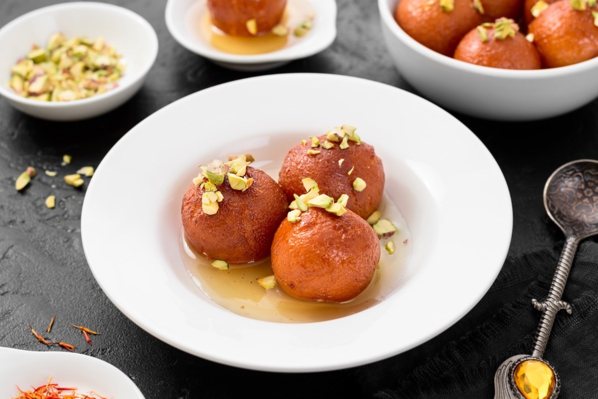 Gulab Jamun auf einem Teller mit gehackten Pistazien und Zuckersirup.