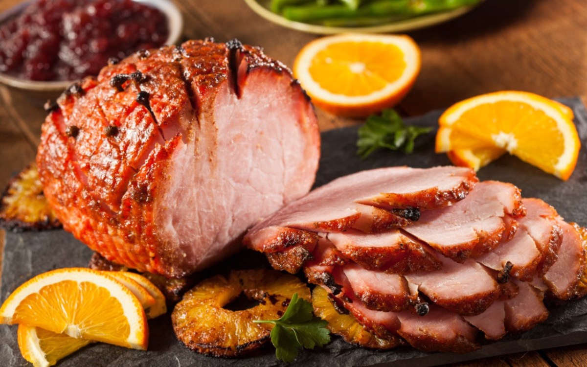 Ein Honey Glazed Ham mit karamellisierten Ananasscheiben, der zur HÃ¤lfte in Scheiben geschnitten wurde.