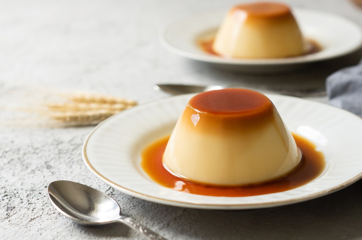 Zwei Karamell-Flan auf je einem kleinen Teller. Drum herum ist Karamellsoße zu sehen.