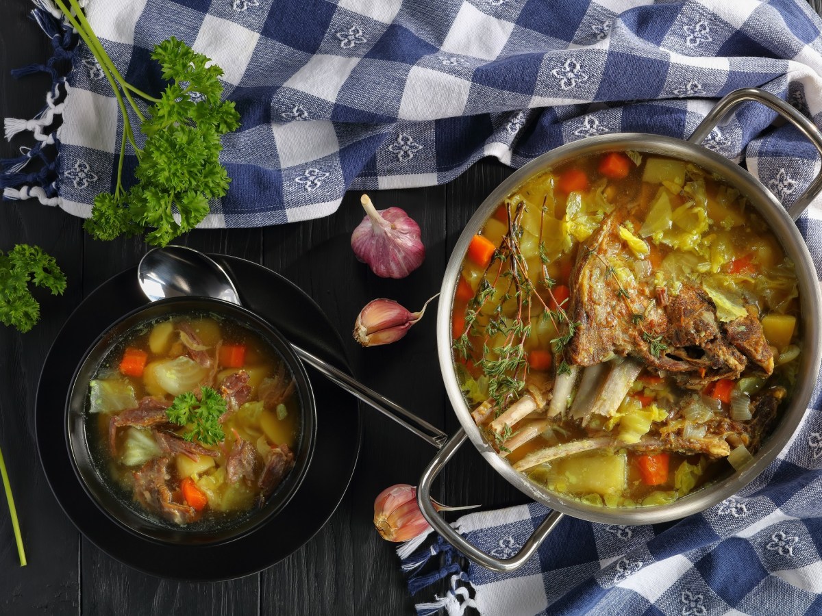 Ein Topf und eine Schale KjÃ¶tsupa: islÃ¤ndische Lammsuppe mit Kohl auf einem karierten Geschirrtuch.