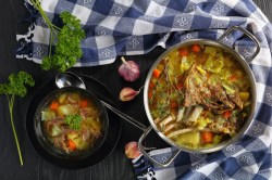 Ein Topf und eine Schale Kjötsupa: isländische Lammsuppe mit Kohl auf einem karierten Geschirrtuch.