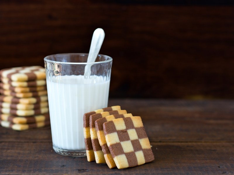 Schwarz-Weiß-Gebäck, das an einem Glas Milch lehnt.