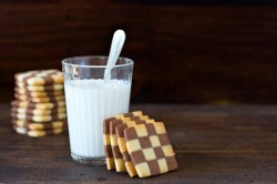 Schwarz-Weiß-Gebäck, das an einem Glas Milch lehnt.