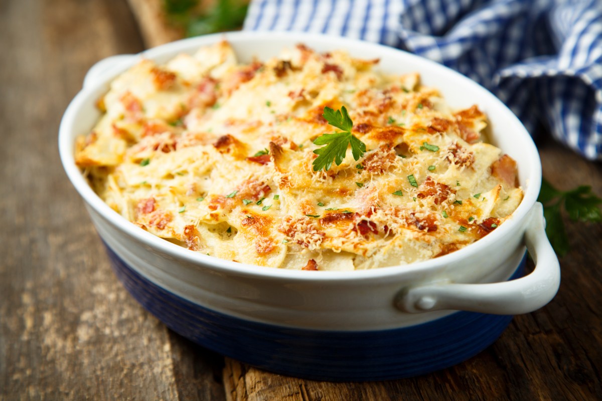 Spitzkohl-Lasagne in ovaler Auflaufform, daneben ein kariertes Geschirrtuch.