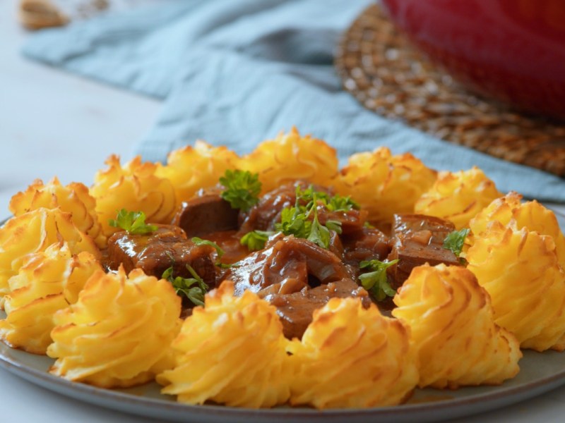 Ein Teller Tofu-Gulasch mit Herzogin-Kartoffeln.