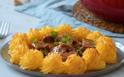 Ein Teller Tofu-Gulasch mit Herzogin-Kartoffeln.